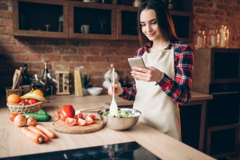 woman-use-phone-while-cooking-vegetable-salad-PQYZ3GB (1)